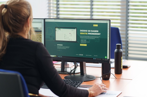 Vrouw die achter haar bureau een website bezoekt