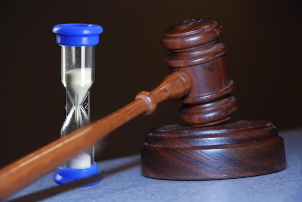 WebBT0524ActueelWoningbouw2 | BouwTotaal Zandloper en een voorzittershamer om uit te beelden dat bezwaarprocedures voor vertraging zorgen