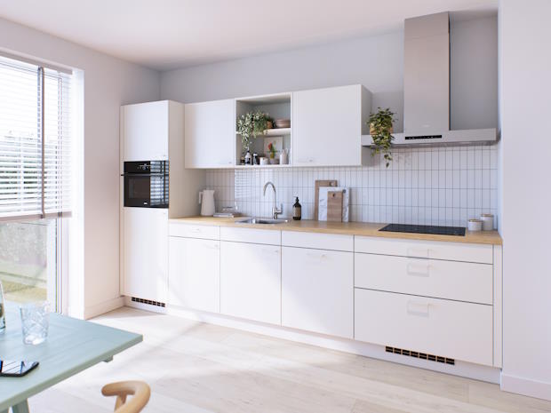 Een moderne keuken gemaakt van van organische, hernieuwbare grondstoffen met witte kasten en een licht houten werkblad. Boven het werkblad zijn open planken en gesloten kasten, met groene planten en keukengerei. Aan de linkerkant staat een ingebouwde oven naast een raam met jaloezieën die daglicht binnenlaten. De vloer is lichtgekleurd en de ruimte heeft een frisse, heldere uitstraling."