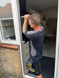 Collin Rolf aan het werk in een deurkozijn.