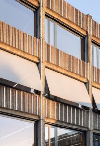 Verticale aluminiumstrips reduceren de zwaarte van de betonarchitectuur en maken de strikte structuur van de gevel losser. De oude ramen werden vervangen en de nieuwe houten ramen met Warema screens met uitvalarmen uitgerust, ter bescherming tegen zonlicht en verblinding. 