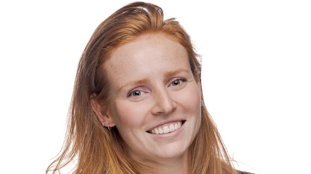 Portrait of a smiling red-haired woman looking at the camera against a white background.