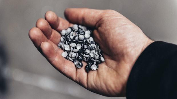A cupped hand holding a handful of small shiny metal pellets or shot pieces.